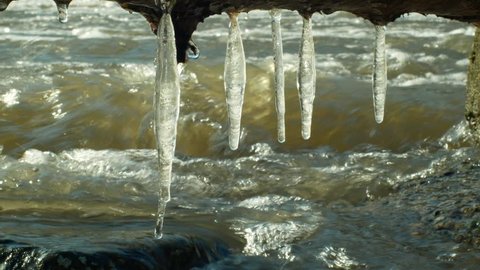 Icicles water river Morava in winter frozen magic and magical white, hanging from overhang, flowing down with ice stones, beautiful scene background, Czech Republic, Europe