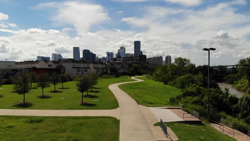 Ascending Drone Footage Flying toward the City of Houston Skyline along a Walking Path next to Buffalo Bayou