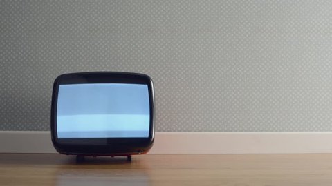 Vintage old television on the floor with static screen, a soccer ball hits it and turns it off