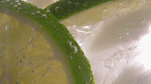 Close up of a refreshing cocktail with lime and bubbles.