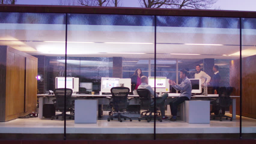 4K Creative business team working together in modern office, seen through the glass from the outside looking in