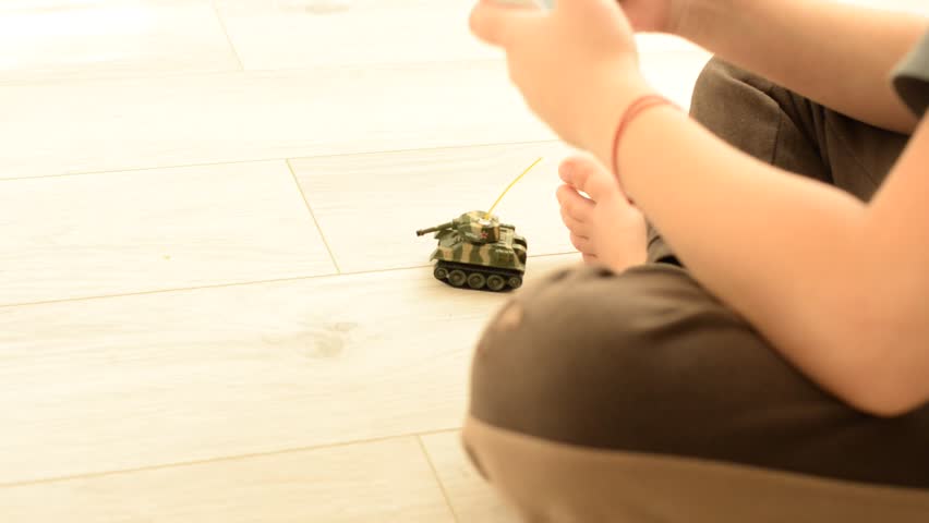 the boy sits on the floor and plays in the tank, the game of tanks, men