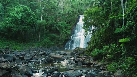 Stunning slow establishing aerial shot of river with huge waterfall in Brazilian green rainforest