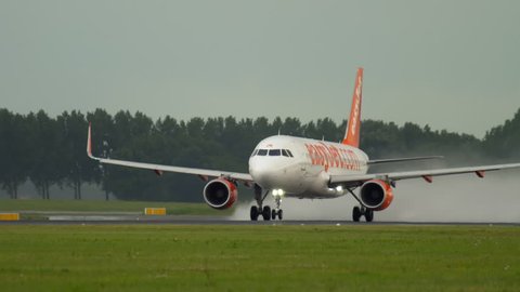 AMSTERDAM, THE NETHERLANDS - JULY 24, 2017: EasyJet Airbus 320 G-EZOK accelerate before departure at Polderbaan 36L, rainy weather, Schiphol Airport, Amsterdam, Holland