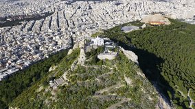 Aerial birds eye view video taken by drone of Lycabettus hill and iconic Saint George chapel on top, Athens historic centre, Attica, Greece