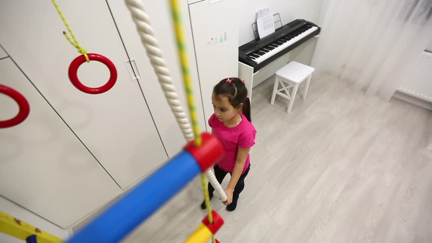 Sport little kid girl home in morning sun light haze jump catch horizontal bar