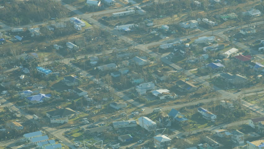 Aerial view of Hurricane devastation residential property damage tarpaulin covered rooftops broken houses stripped trees Florida Panhandle America RED WEAPON