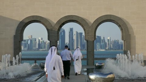 Doha, Qatar, Feb 2019: Group of Arabs and westerners walking towards a viewpoint to the business center of Doha with skyscrapers 