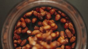 TOP VIEW: Peeled peanuts falling into a glass jar - Slow Motion - Powered by Shutterstock - Get 15% off with code: PIKWIZARD15