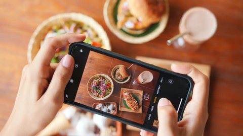 Female Taking Photo of Fast Food Using Mobile Phone in Vegan Restaurant. 4K Slowmotion Flatlay Food Photography on Wooden Table in American Diner. Bali, Indonesia.