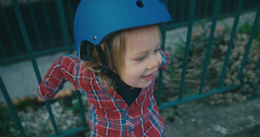 A happy little toddler wearing a helmet is pulling funny faces