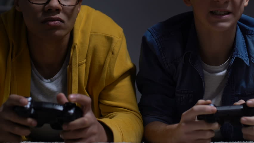 Two male friends celebrating winning in video game, weekend night sleepover