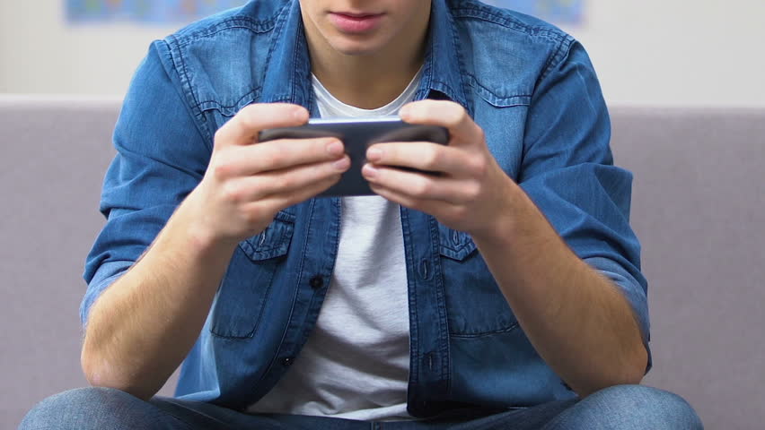 Entranced teenager playing fast-paced video game on smartphone, leisure time