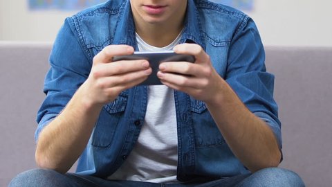 Entranced teenager playing fast-paced video game on smartphone, leisure time