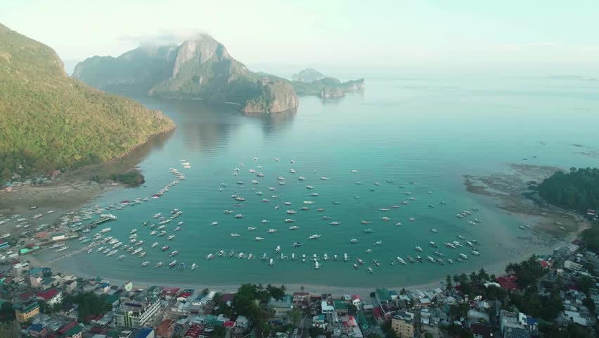 Aerial drone view of boats anchored in the bay with clear and turquoise water. Boat and yacht in the tropical lagoon. Tropical landscape. El Nido, Palawan island, Philippines.