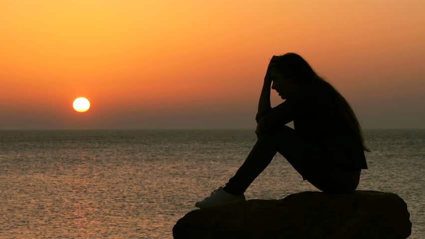 Side view portrait of a sad woman silhouette complaining at sunset on the beach | Shutterstock HD Video #1025193668