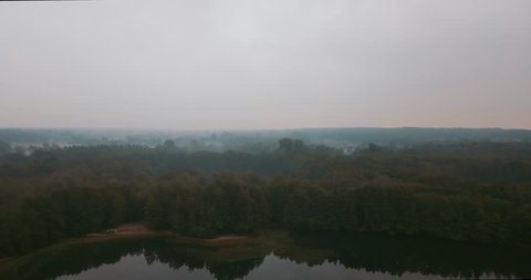a beautiful lake in the middle of a forest on a foggy morning.