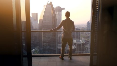 One Young Man Standing on Office Balcony Overlooking City Skyline