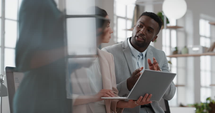 Young team leader black woman brainstorming with businessman colleague using laptop computer showing ideas pointing at screen working together in office