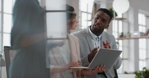 young team leader black woman brainstorming with businessman colleague using laptop computer showing ideas pointing at screen working together in office