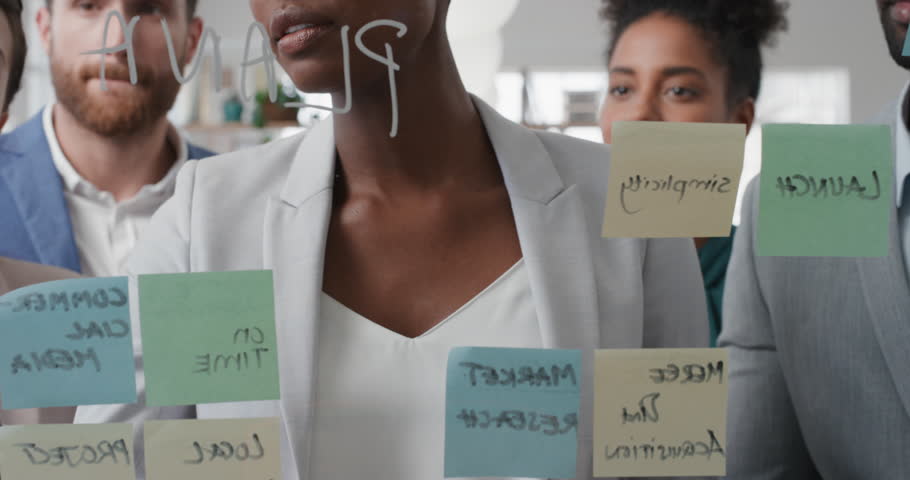 Corporate business people using sticky notes brainstorming problem solving strategy on glass whiteboard team leader woman showing solution for project deadline in office meeting | Shutterstock HD Video #1025208716