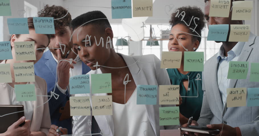Corporate business people using sticky notes brainstorming problem solving strategy on glass whiteboard team leader woman showing solution for project deadline in office meeting | Shutterstock HD Video #1025208725