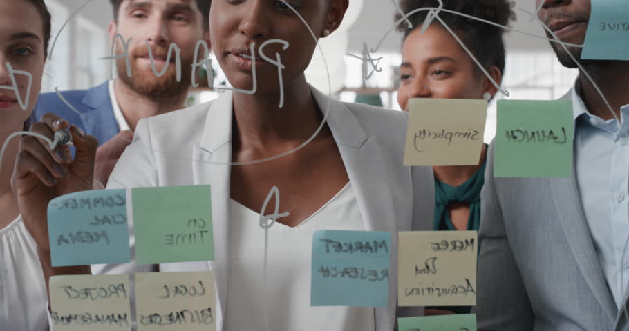 Corporate business people using sticky notes brainstorming problem solving strategy on glass whiteboard team leader woman showing solution for project deadline in office meeting | Shutterstock HD Video #1025208728