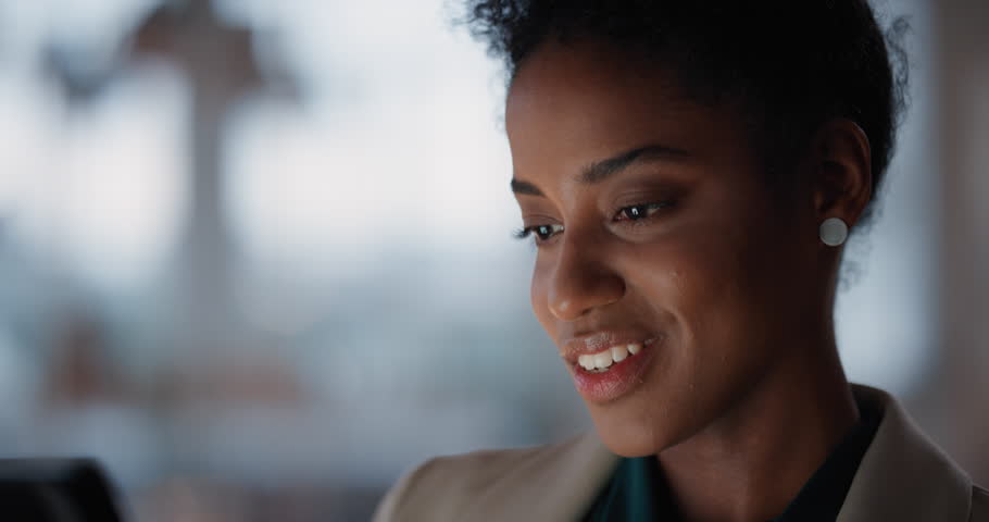 Beautiful black business woman using tablet computer working late in office browsing information looking at data on digital touchscreen | Shutterstock HD Video #1025212004
