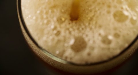 Beer is pouring and foaming in Glass Top View closeup Slow motion video