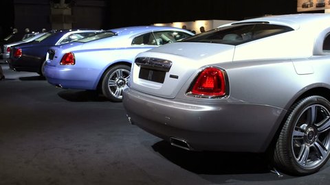 AMSTERDAM, THE NETHERLANDS - APRIL 16, 2015: Two Rolls Royce Wraith luxury coupe cars on display at the Amsterdam motor show. A woman walks past the cars.