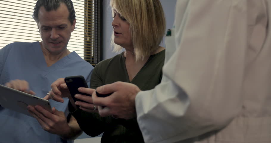 Patient comparing health data on her phone with the medical records on her healthcare providers digital tablet and doctor's smartphone