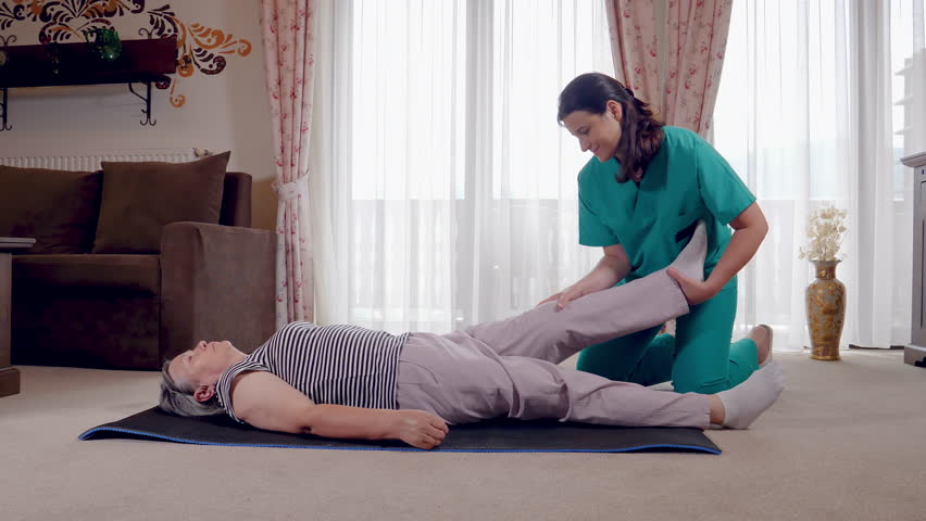 Young therapist exercising with older female patient in nursing home. Nurse giving leg massage to senior woman in a retirement home. 4k hand held movement | Shutterstock HD Video #1025217926