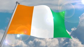 The flag of République de Côte d'Ivoire develops in the wind against a blue sky with cumulus clouds and a flash on the lens from the sun. 4K video is looped and decoded from a 3D program.