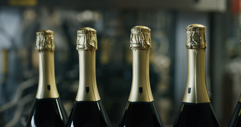 Slow motion close up of champagne wine producing and bottling process using automated conveyors equipment. 
