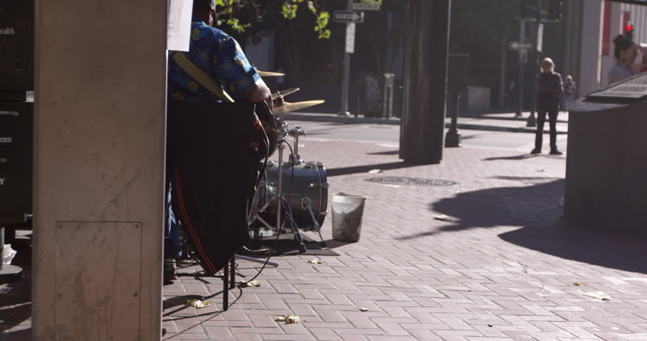 Street performer busker playing drumbs on city street