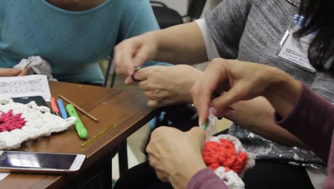 Odessa,Ukraine - December 22 2018: Close-up. Woman teacher  conducts the women a masterclass on crochet lace or clothing. Taken from a moving camera on a slider. Camera dolly