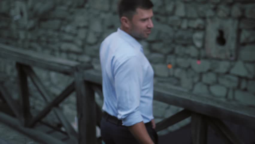 Wedding couple stand on the wooden bridge in the front of old fortress.