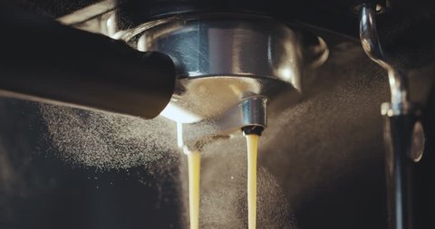 Pouring coffee stream from professional machine in cup. Barista man making double espresso, using filter holder. Flowing fresh ground coffee. Drinking roasted black coffee in the morning