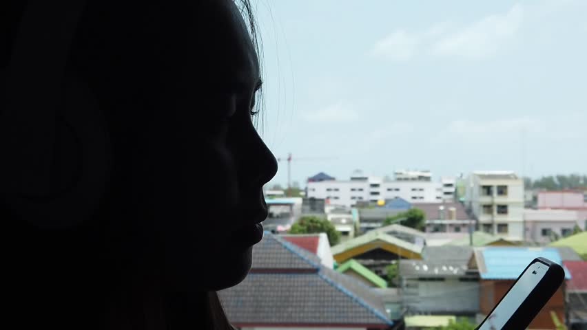 Beautiful Asian woman happy smiling and enjoy listening to music with headphones at home. With noise blurry background. Slow motion shot.