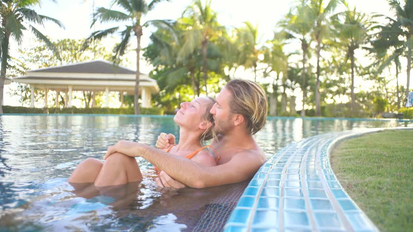 Love birds couple enjoying relaxation in swimming pool at sunset | Shutterstock HD Video #1025256026