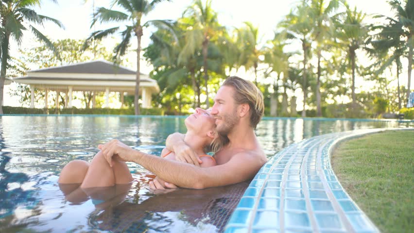 Love birds couple enjoying relaxation in swimming pool at sunset | Shutterstock HD Video #1025256035