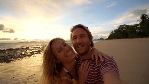 Couple on vacation taking selfie on the beach at sunset. Young couple selfies point of view 