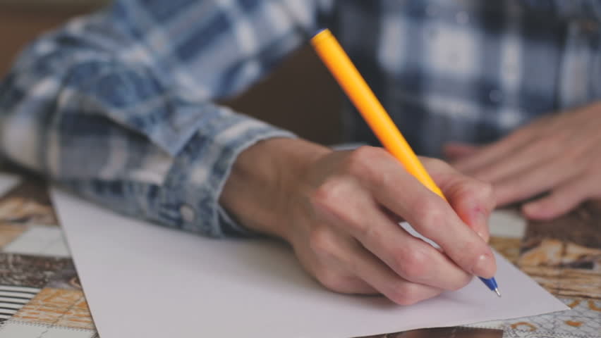 Lifestyle concept. A girl in a blue plaid shirt sits at a table and writes down her life goals.