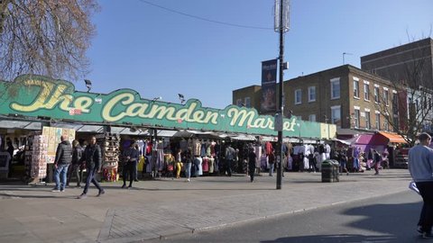 London, England - February 27, 2019: Camden Town - Locals and tourists passing by the famous Camden Market sign and shops on a clear sky day.