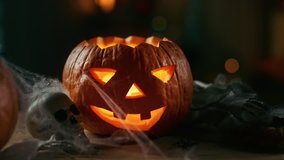 Halloween Still Life Colorful Theme: Scary Decorated Dark Room with Table Covered in Spider Webs, Burning Pumpkin, Candlestick, Witch's Hat and Skeleton.Background: Silhouette of Monster Walking By - Powered by Shutterstock - Get 15% off with code: PIKWIZARD15