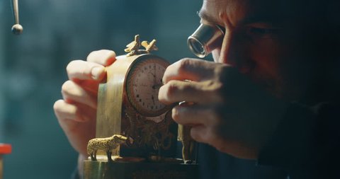 Slow motion close up of a professional watchmaker repairer working on a vintage mechanism clock in a workshop. Shot in 8K.