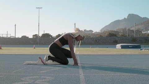 Side view of a female athlete starting her sprint on a running track. Runner taking off from the starting blocks on running track.
