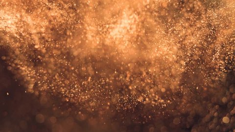 Elegant, detailed, and golden particles flow with shallow depth of field underwaterの動画素材