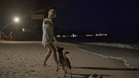 Young blond woman playing with a dog on a beach - slow motion