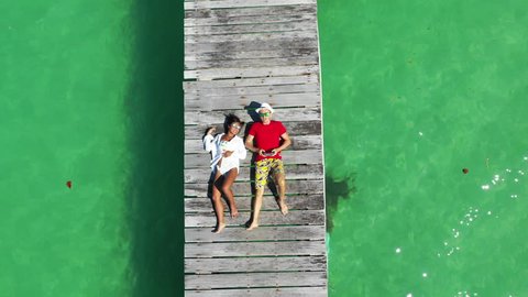 01 Aerial 4k footage from different drone camera angles: Couple in love lying in the sun on scenery wooden bridge on background amazing tropical sand beach on atoll island resort 